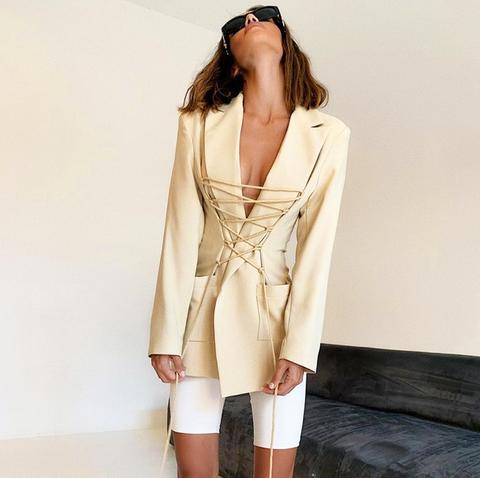 Blazer feminino estruturado com comprimento alongado e detalhe de amarração frontal ajustável, modelagem acinturada moderna