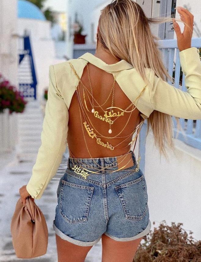 Blazer feminino estruturado com recorte profundo nas costas e correntes douradas decorativas, modelagem ajustada e tecido sofisticado