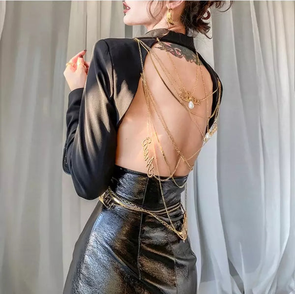 Blazer feminino estruturado com recorte profundo nas costas e correntes douradas decorativas, modelagem ajustada e tecido sofisticado