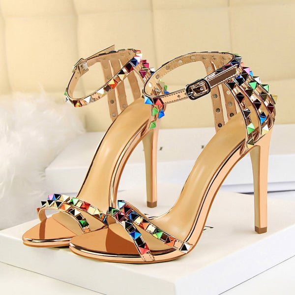 Sandália feminina salto alto fino com tiras cravejadas de spikes coloridos e fechamento por fivela