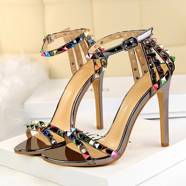 Sandália feminina salto alto fino com tiras cravejadas de spikes coloridos e fechamento por fivela