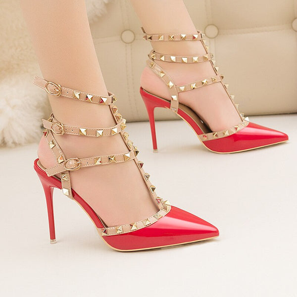 Scarpin salto alto fino com acabamento em verniz, bico fino, tiras com spikes metálicos e fechamento com fivela