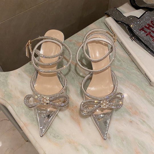 Scarpin salto alto fino feminino com bico fino, cabedal transparente, laço e corrente espiral de strass