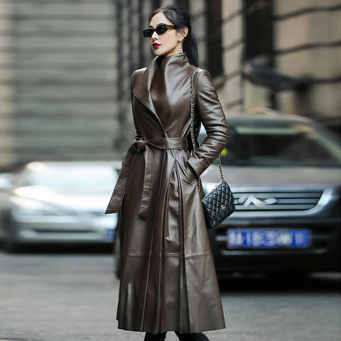 Sobretudo feminino longo de couro sintético marrom, com gola alta, faixa na cintura e modelagem estruturada, ideal para o inverno