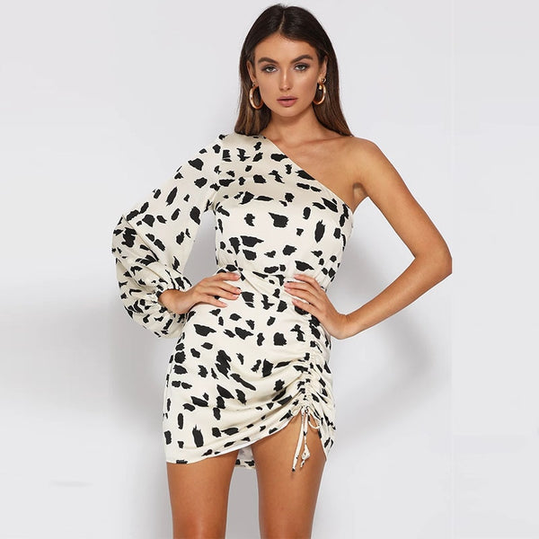Vestido curto com estampa dálmata, ombro único, manga bufante e detalhe drapeado.