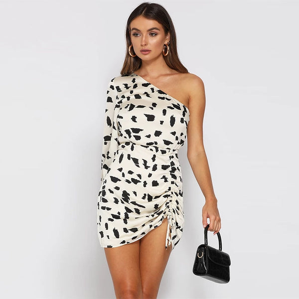 Vestido curto com estampa dálmata, ombro único, manga bufante e detalhe drapeado.