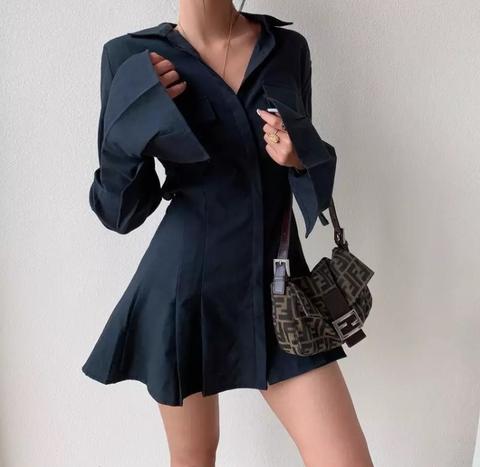 Vestido curto elegante com botões frontais, manga longa, punho estruturado e barra levemente rodada em tecido de alfaiataria premium.